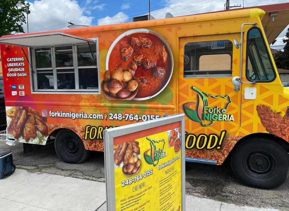 The bright orange Fork in Nigeria food truck, parked and serving